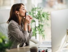 A woman sitting at a desk kisses a card.