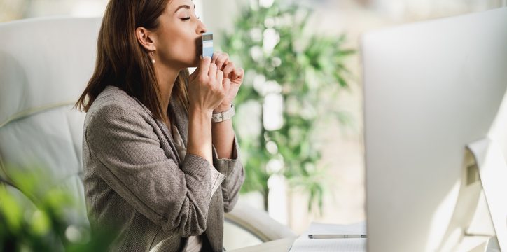 A woman sitting at a desk kisses a card.